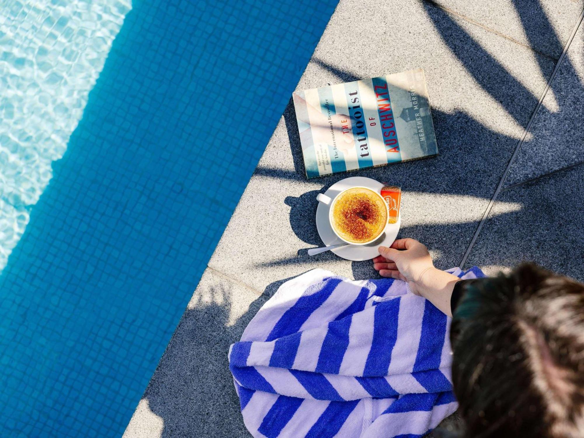 Pullman Brisbane Airport Hotel Bagian luar foto A woman reading a book by the pool
